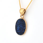Gold necklace with a blue pendant on a white background