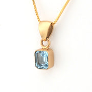 Gold pendant with a blue gemstone on a white background