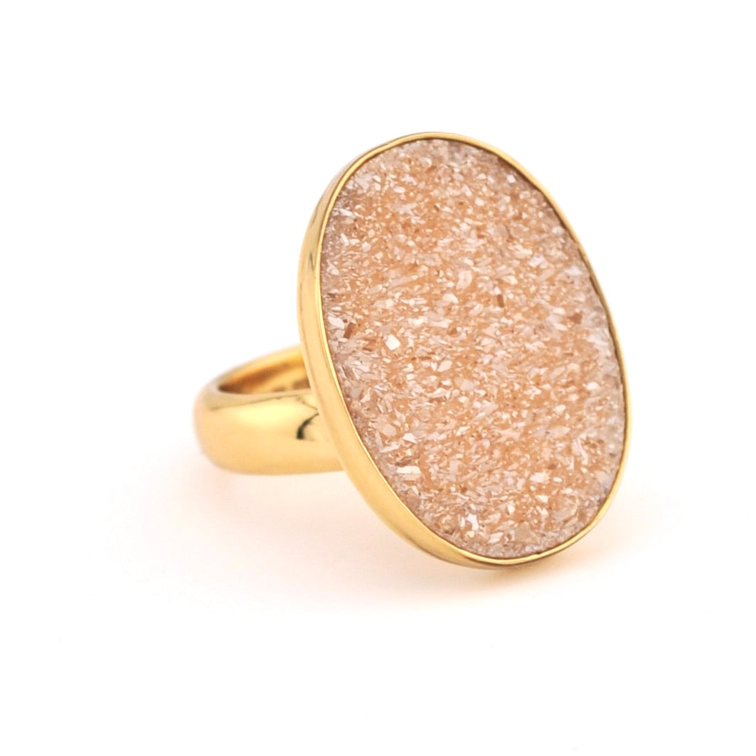 Gold ring with a beige druzy stone on a white background
