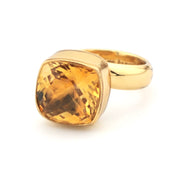 Gold ring with a large yellow gemstone on a white background