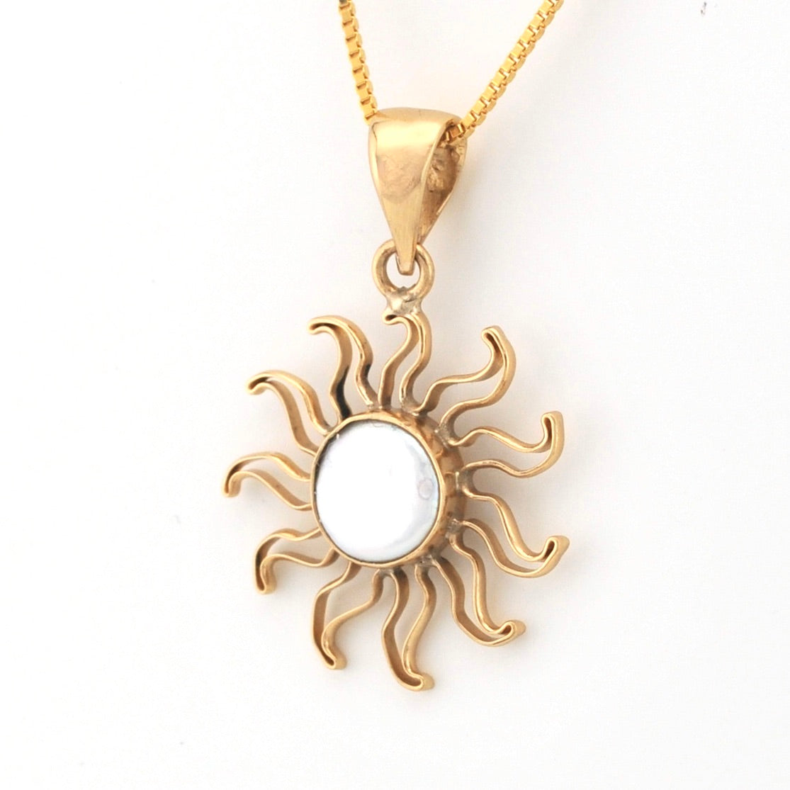 Gold sun-shaped pendant on a white background