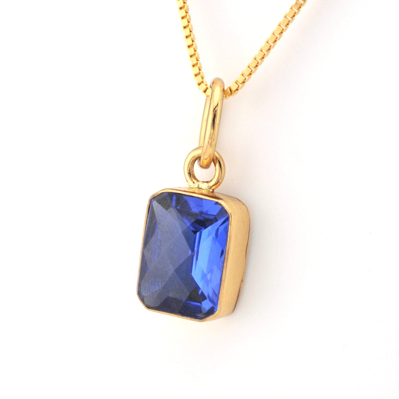 Gold necklace with a blue pendant on a white background