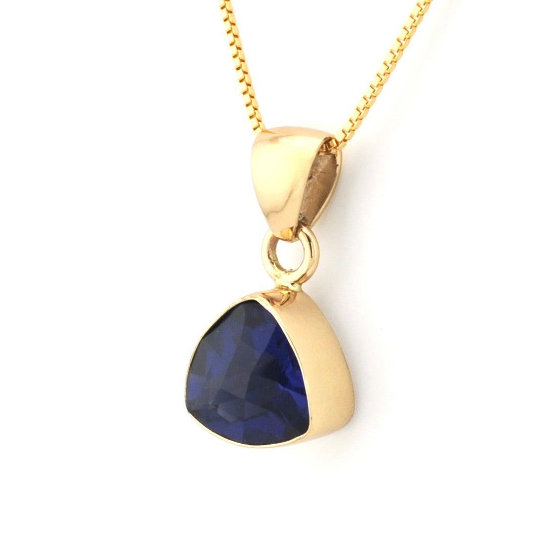 A gold pendant necklace featuring a faceted dark blue teardrop-shaped gemstone in a gold bezel setting, suspended from a delicate gold chain against a plain white background.