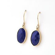 Gold earrings with blue oval stones on a white background