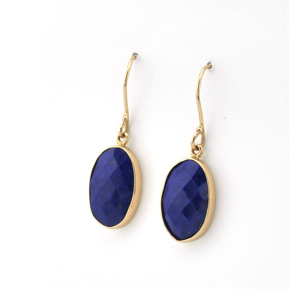 Gold earrings with blue oval stones on a white background