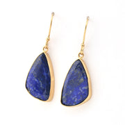 Pair of gold earrings with blue stone drops on a white background