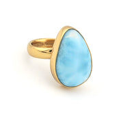 Gold ring with a large blue stone on a white background