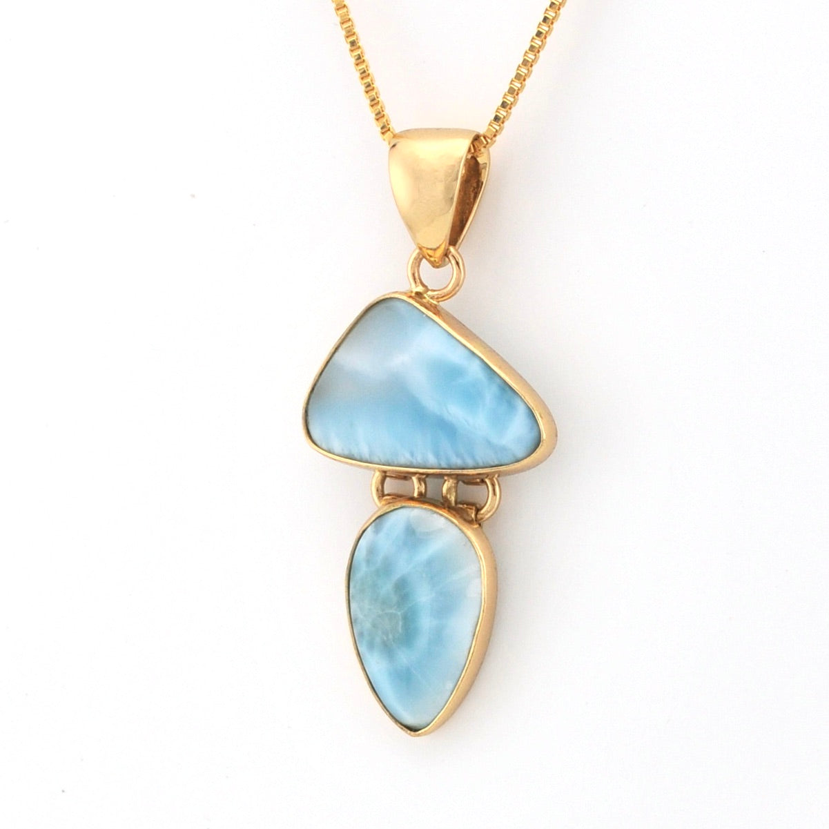 Gold necklace with a blue pendant on a white background