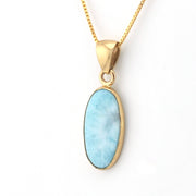 Gold necklace with a blue pendant on a white background