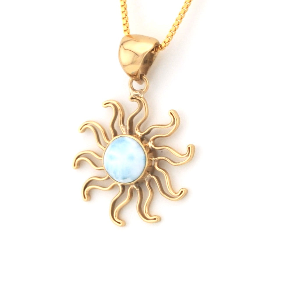 Gold sun-shaped pendant with a light blue center on a white background