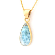 Gold necklace with a teardrop-shaped larimar pendant on a white background