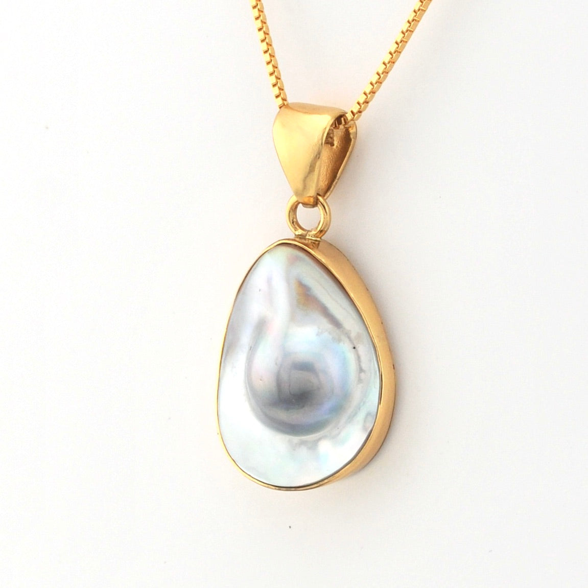 Gold pendant with a large teardrop-shaped pearl on a white background