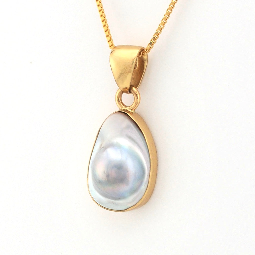 Gold pendant with a pearl on a white background
