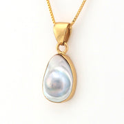 Gold pendant with a pearl on a white background