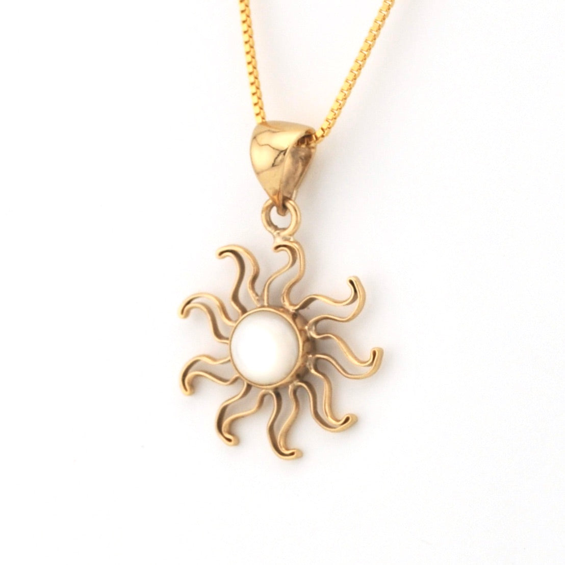 Gold sun-shaped pendant on a chain against a white background