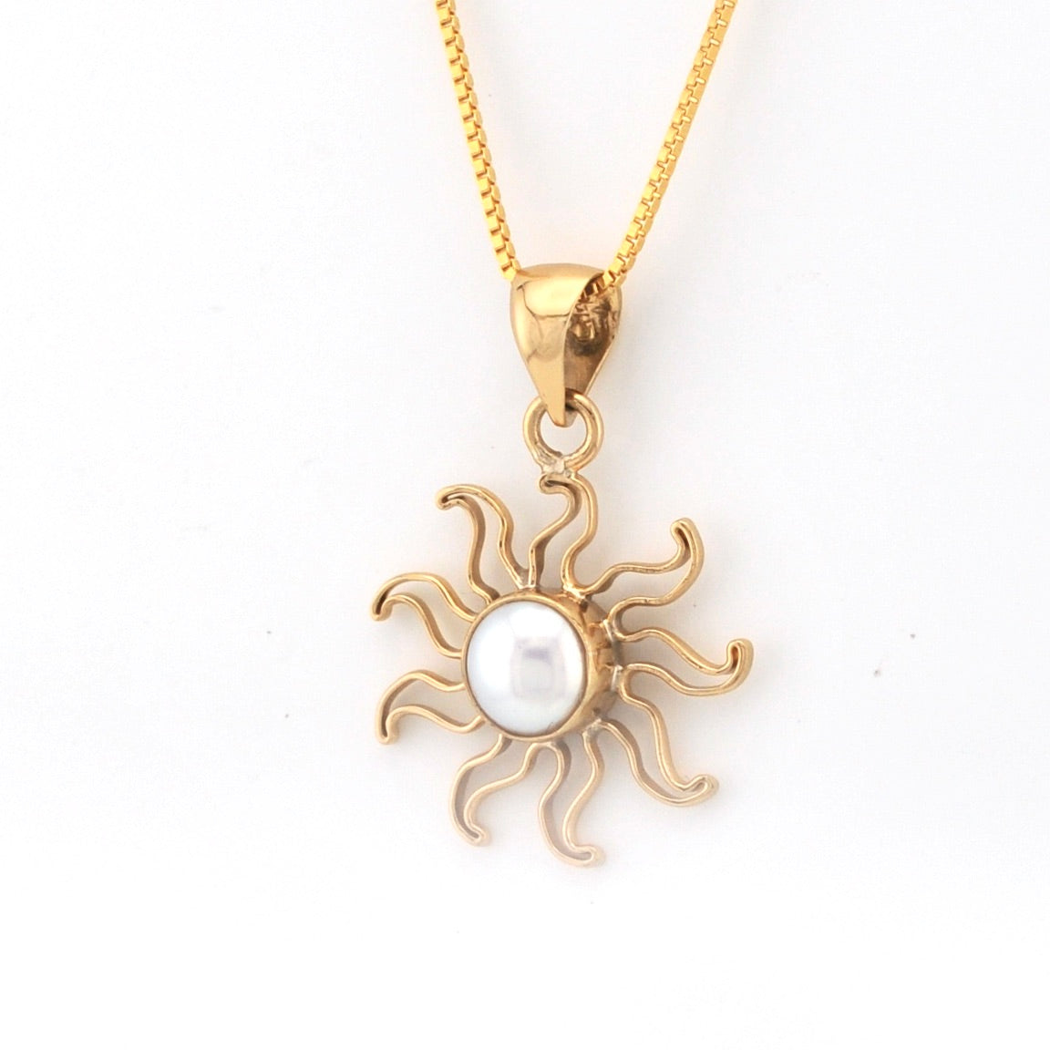 Gold sun-shaped pendant with a pearl center on a white background