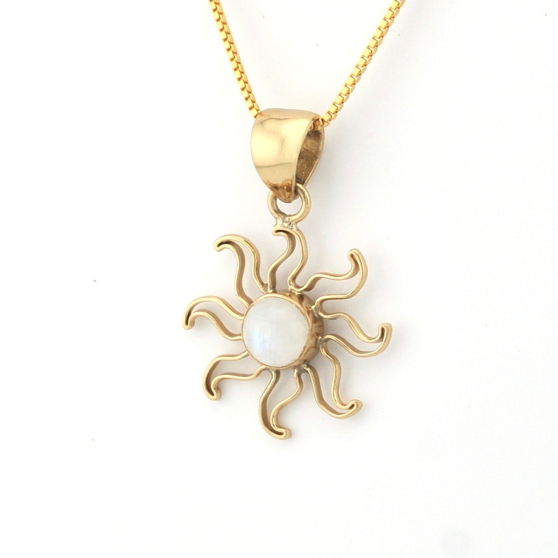 Gold sun-shaped pendant with a white center on a gold chain against a white background