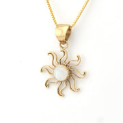 Gold sun-shaped pendant with a white center on a gold chain against a white background
