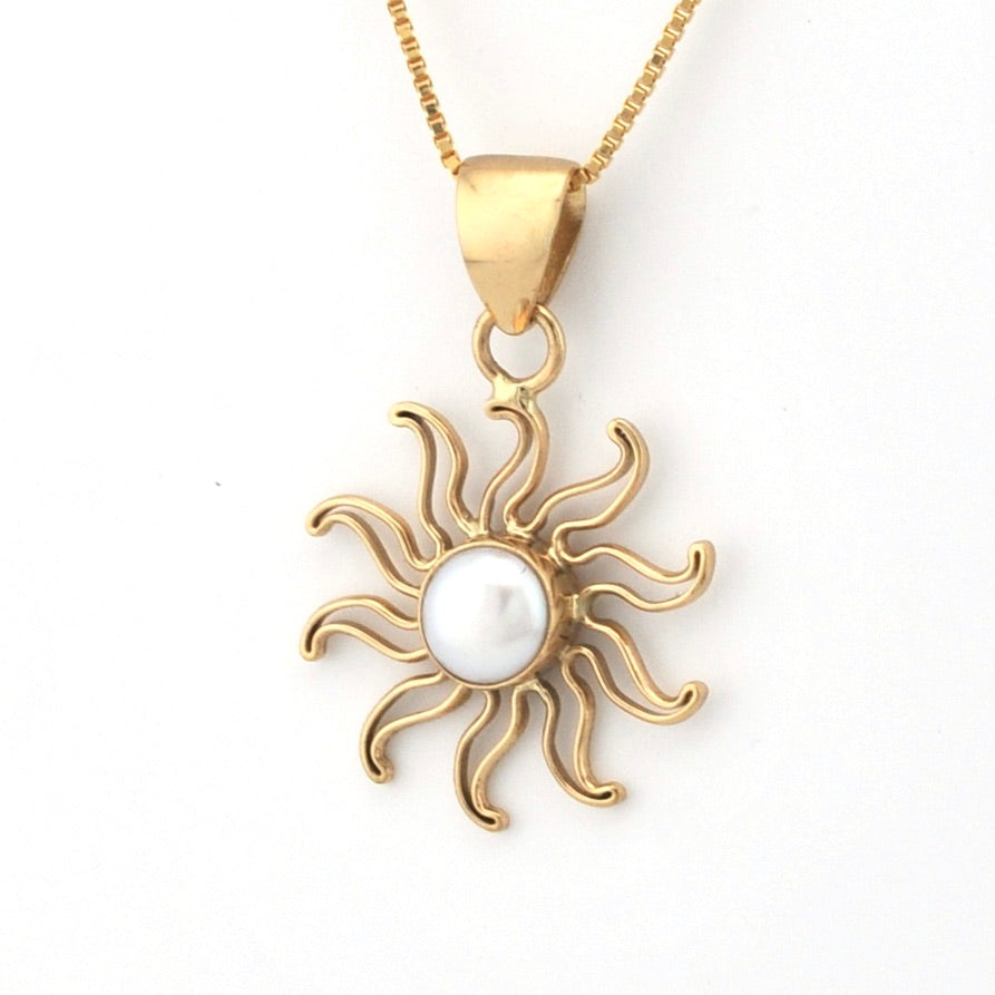 Gold sun-shaped pendant with a pearl center on a white background