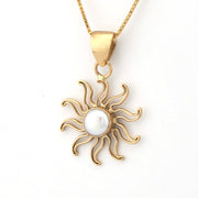 Gold sun-shaped pendant with a pearl center on a white background