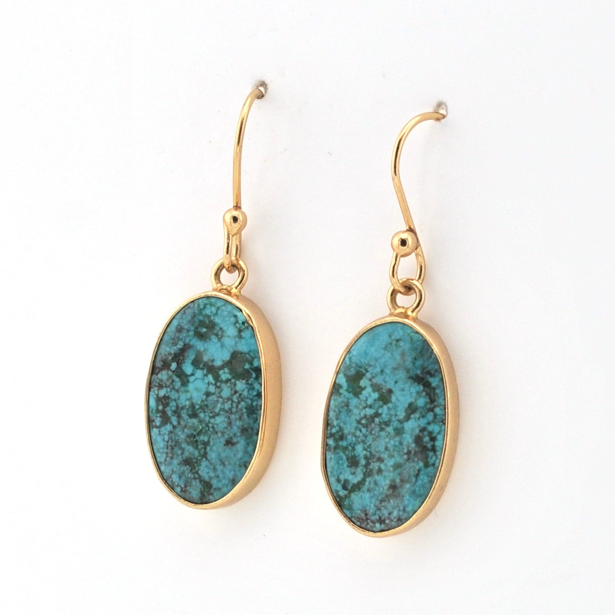 Gold earrings with blue stone drops on a white background