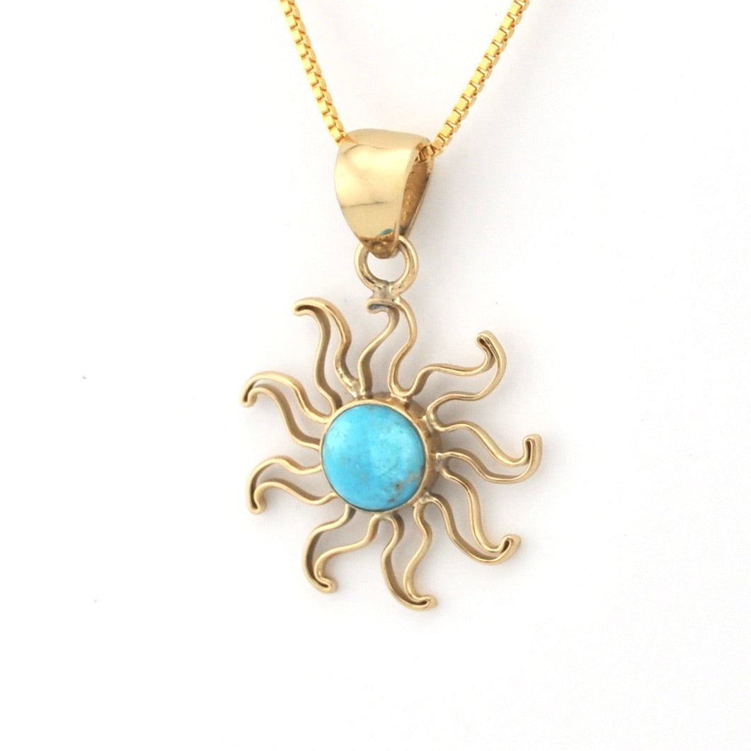 Gold sun-shaped pendant with turquoise center on a white background