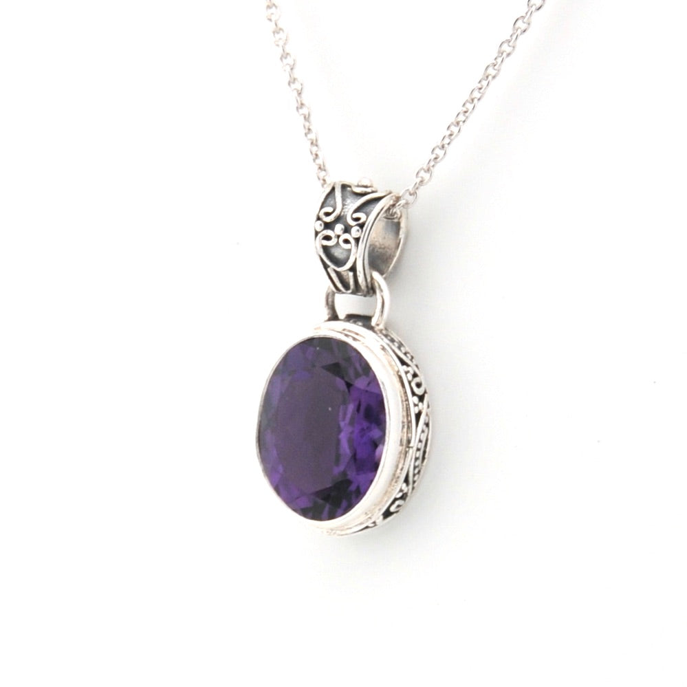 Silver pendant with a purple gemstone on a white background