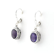 Pair of silver earrings with purple gemstones on a white background