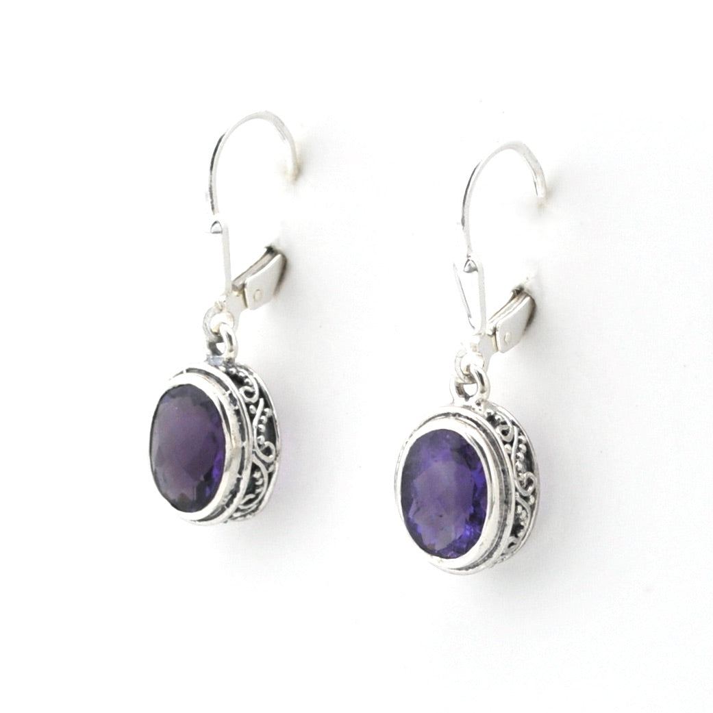 Pair of silver earrings with purple gemstones on a white background