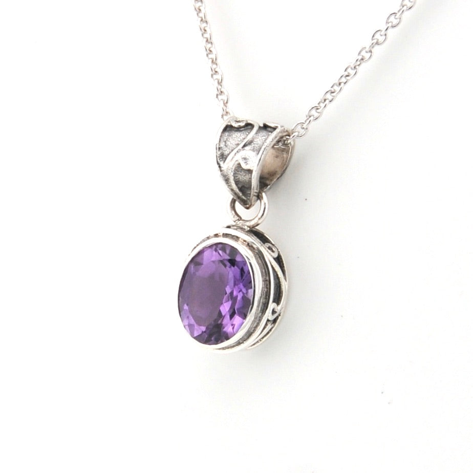 Silver necklace with a purple gemstone pendant on a white background