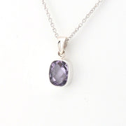 Purple gemstone pendant on a silver chain against a white background