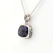 Silver necklace with a purple gemstone pendant on a white background