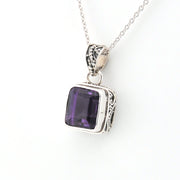 Silver pendant with a purple gemstone on a white background