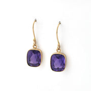 Pair of gold earrings with purple gemstones on a white background