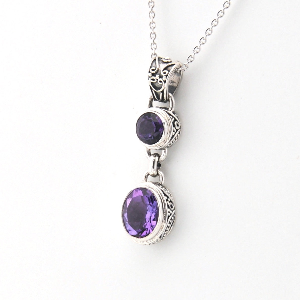 Silver necklace with purple gemstone pendants on a white background