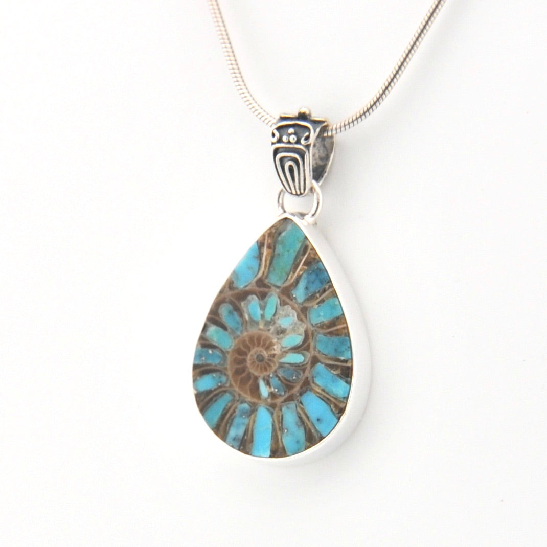 Teardrop-shaped pendant with blue and brown design on a white background