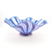 A decorative glass bowl with a wavy, ruffled rim and a small base, featuring a marbled pattern of blue, purple, and white swirls, photographed on a white background.