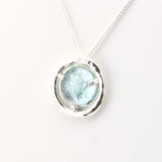 Necklace with a round pendant featuring a light blue stone on a white background