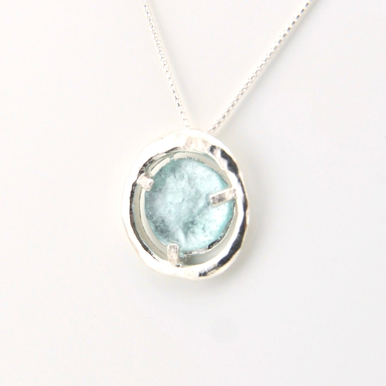 Necklace with a round pendant featuring a light blue stone on a white background