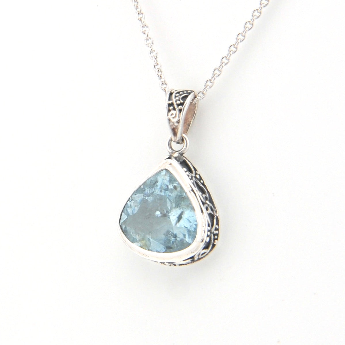Silver pendant with a blue gemstone on a white background