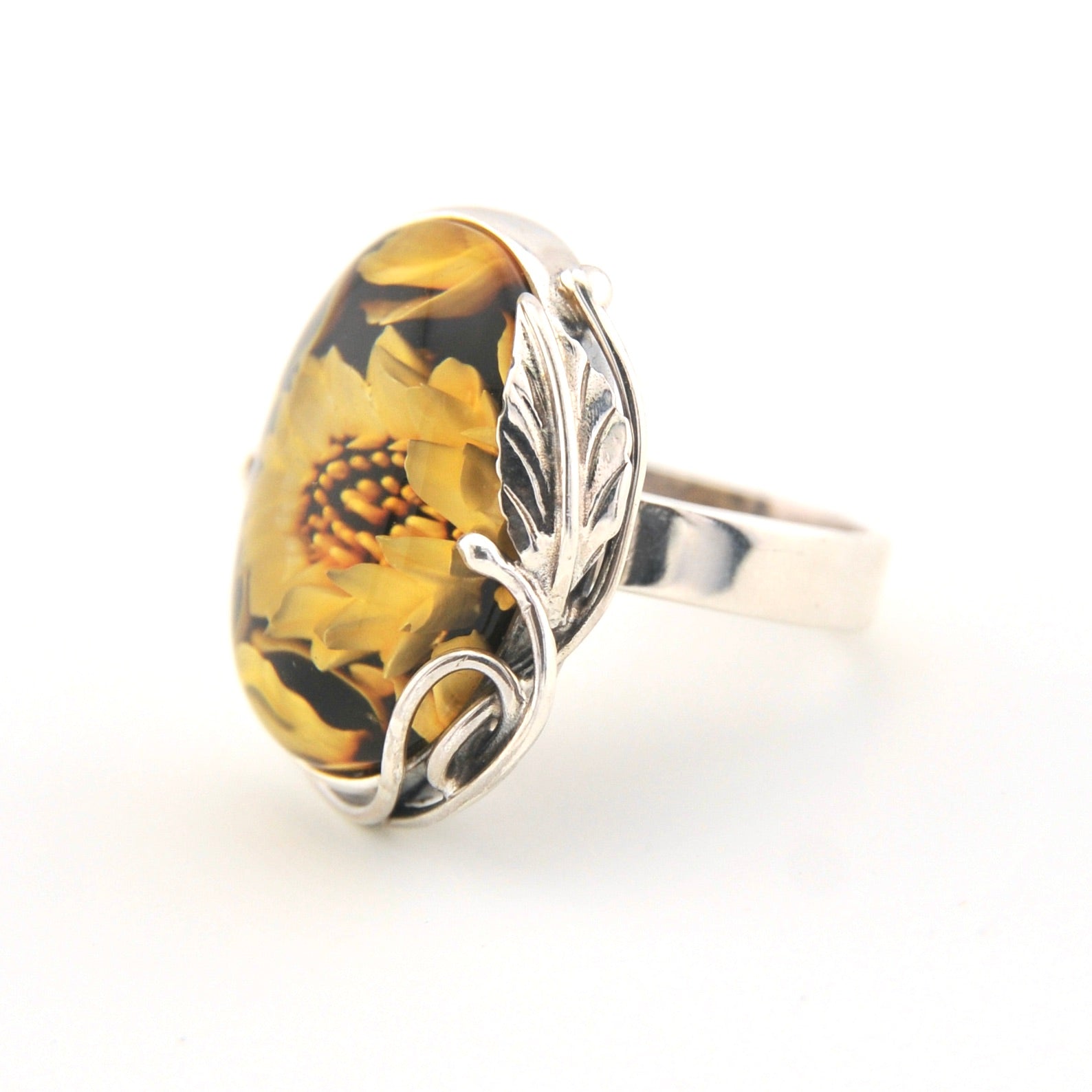 Silver ring with a yellow floral design on a white background