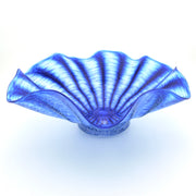 A blue glass bowl with a scalloped, fan-like rim and radiating textured lines, photographed on a white background.