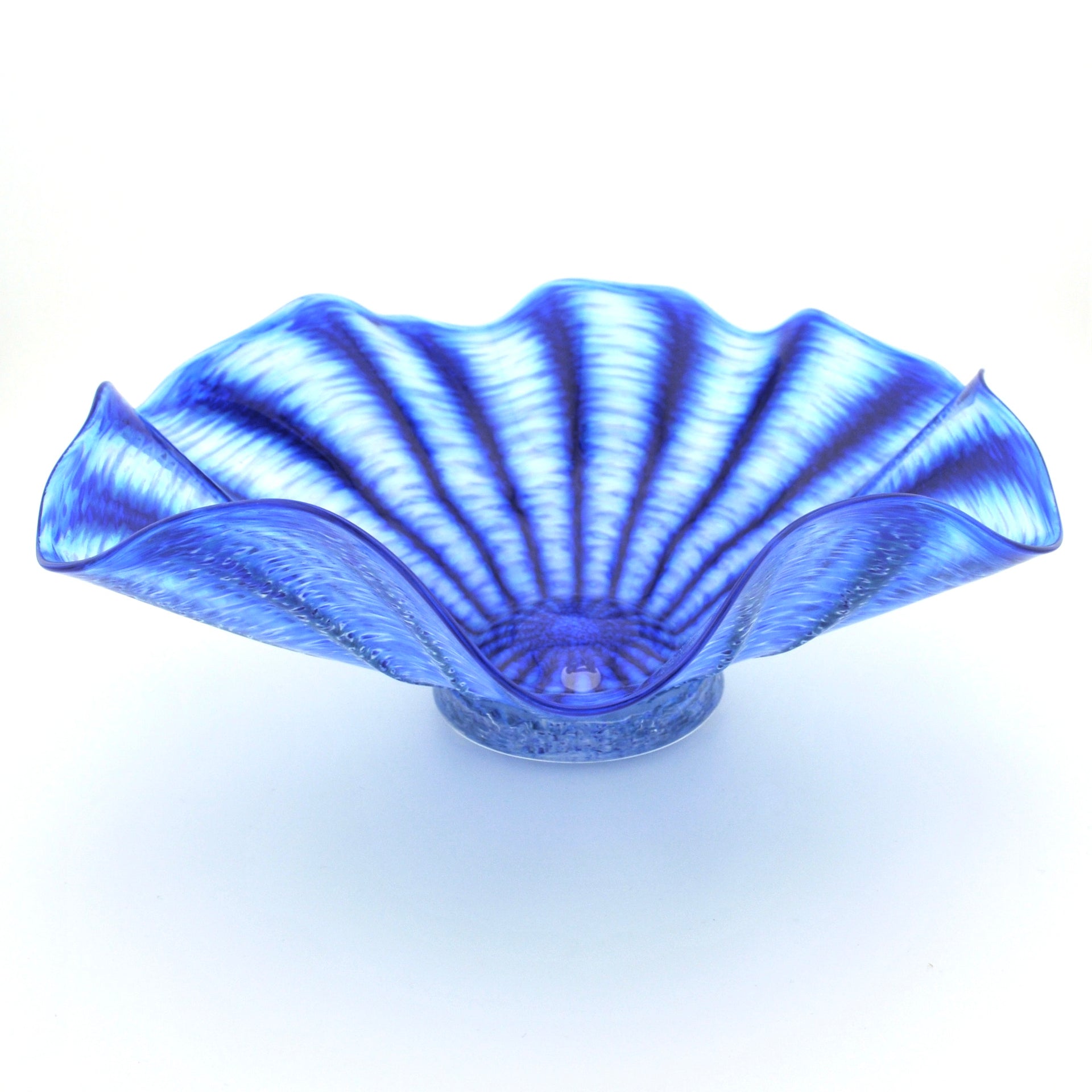 A blue glass bowl with a scalloped, fan-like rim and radiating textured lines, photographed on a white background.
