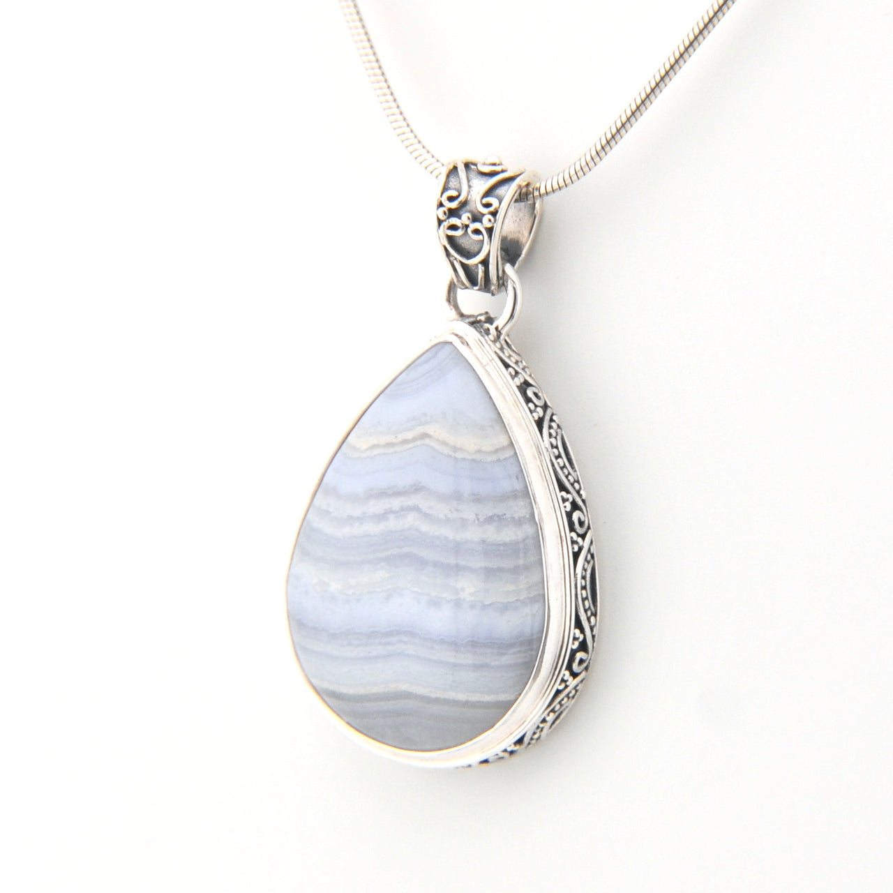 Teardrop-shaped pendant with blue and white pattern on a silver chain against a white background