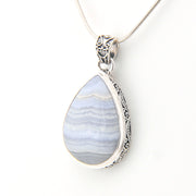 Teardrop-shaped pendant with blue and white pattern on a silver chain against a white background
