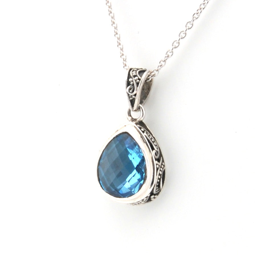 Silver pendant with a blue gemstone on a white background