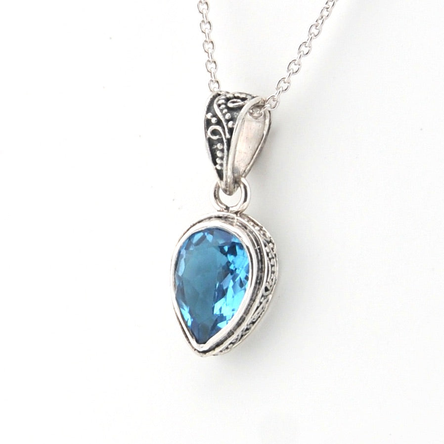 Silver pendant with a blue gemstone on a white background