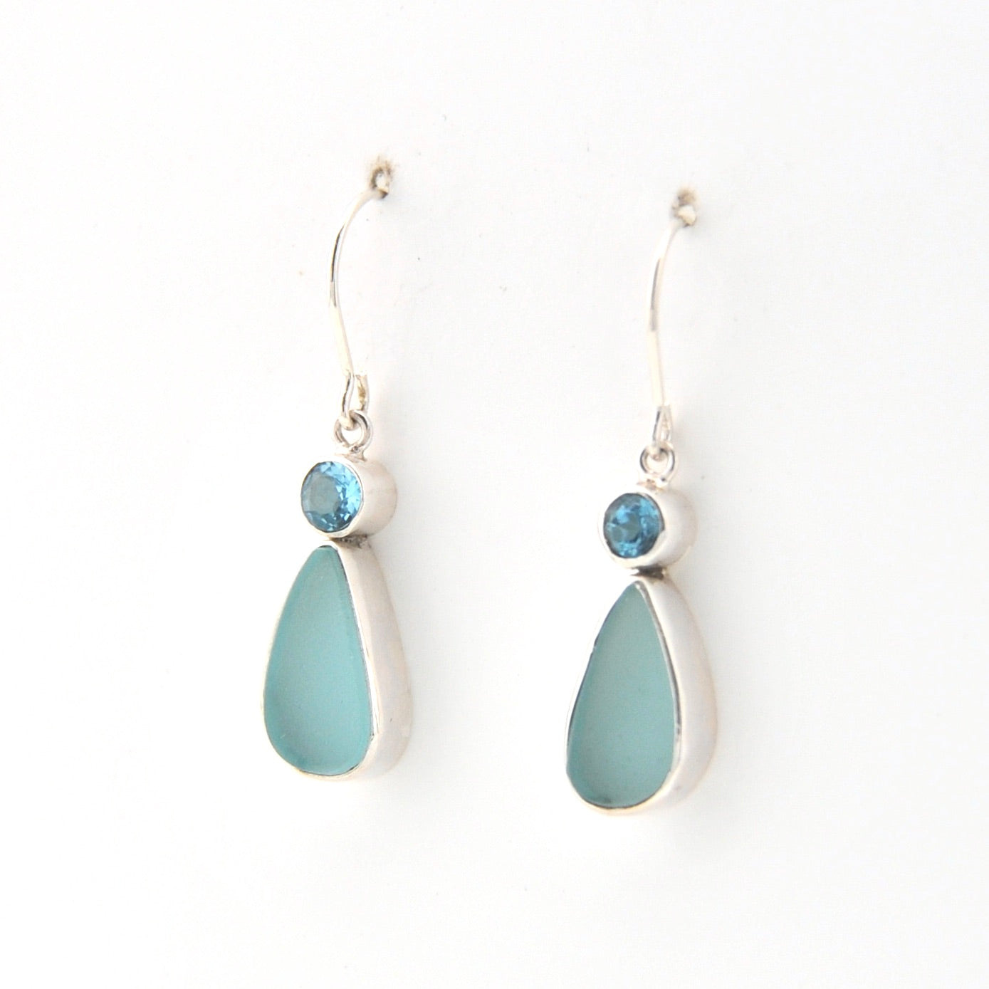 Pair of earrings with blue teardrop stones on a white background
