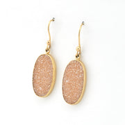 Pair of gold-framed beige druzy earrings on a white background