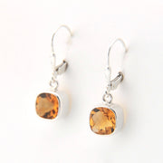 Pair of silver earrings with amber-colored gemstones on a white background